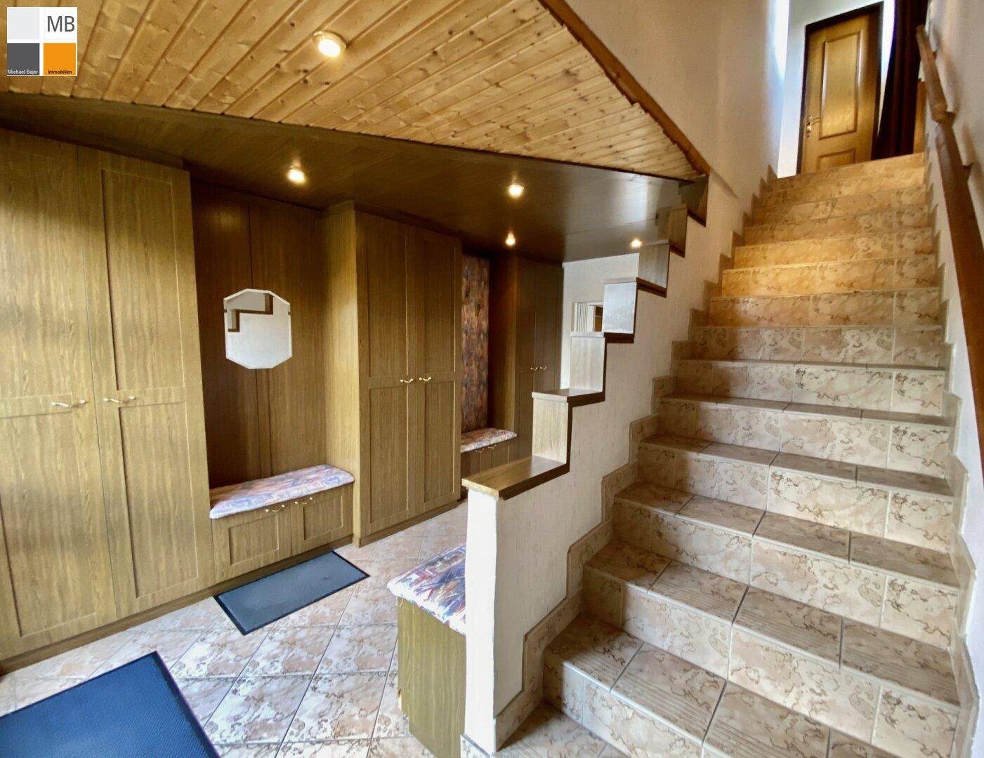 Geräumiger Flur mit Holzvertäfelung, Einbauschränken und gefliester Treppe zum Obergeschoss.