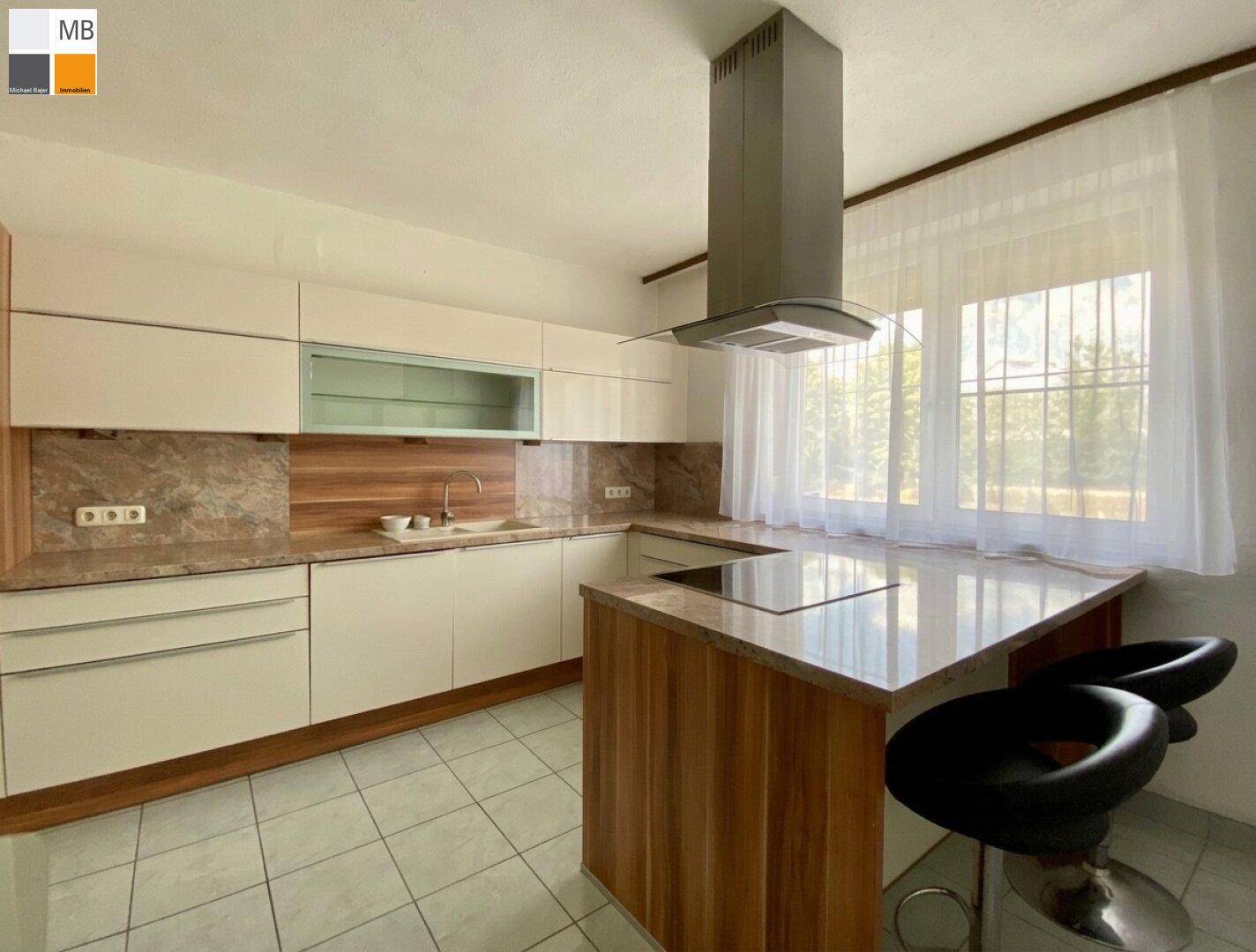 Moderne Küche mit hellen Schränken, Kücheninsel mit Kochfeld und großem Fenster.