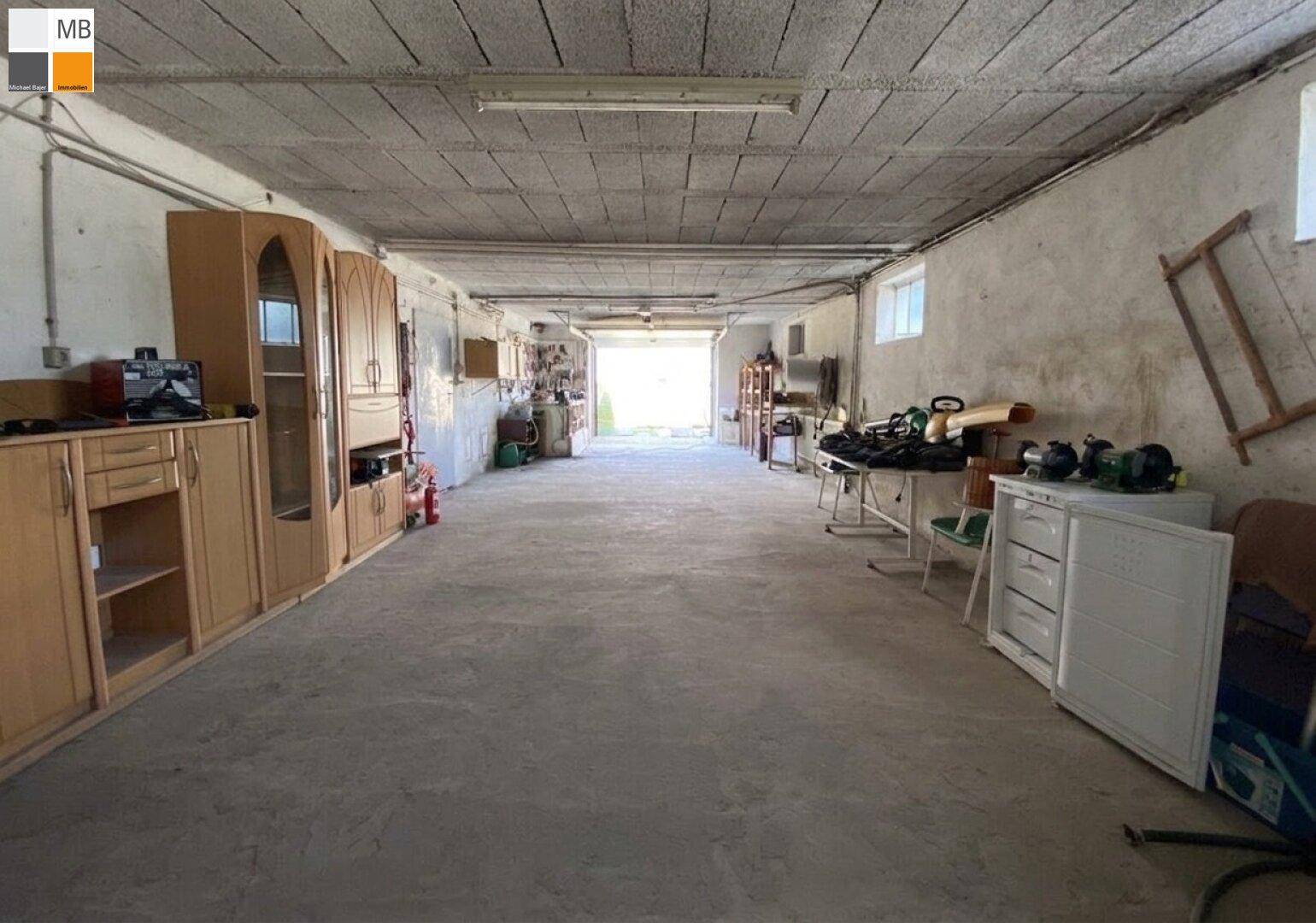 Geräumige Garage oder Werkstatt mit Betonboden und Lagerregalen.