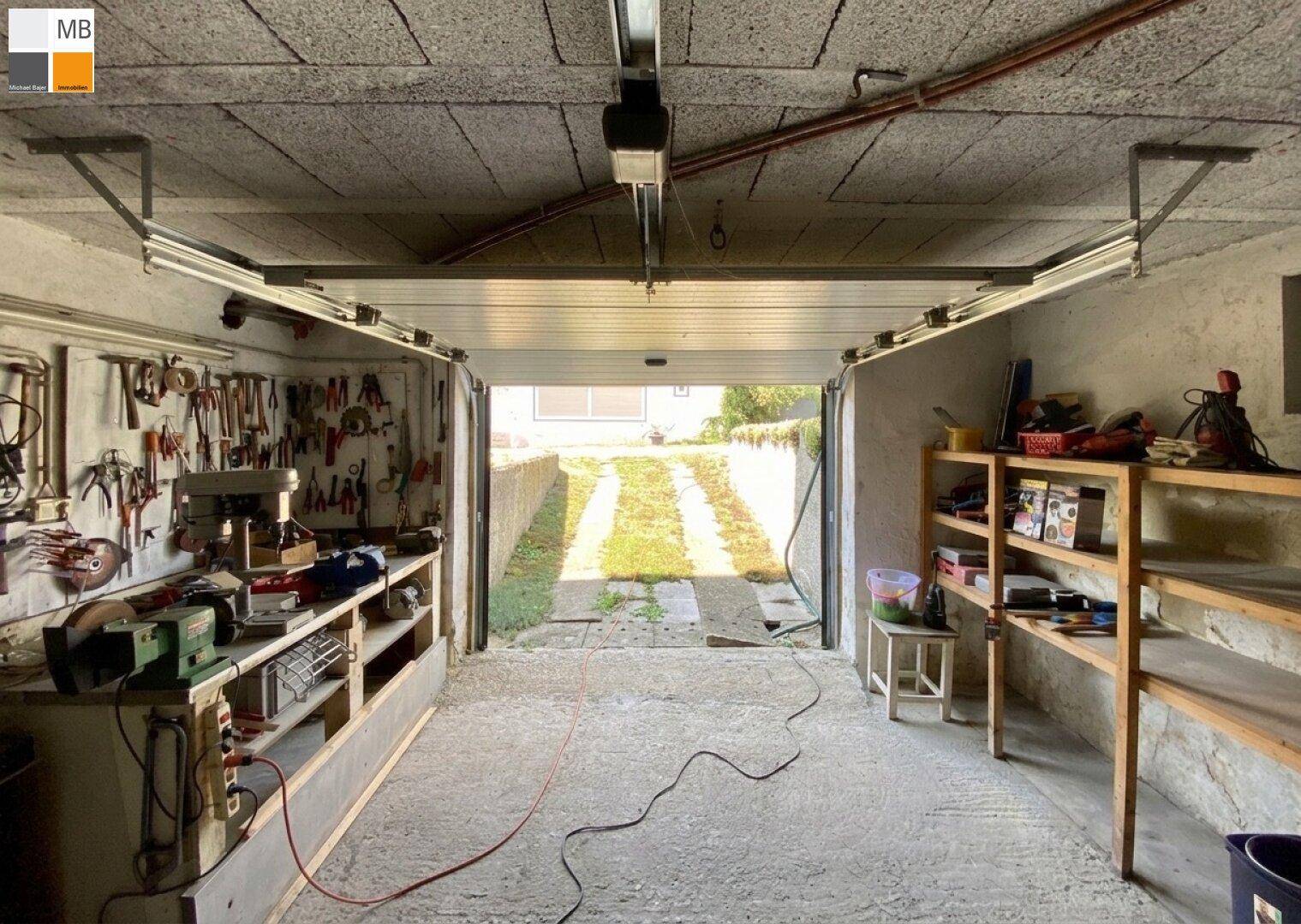 Geräumige Garage, die als Werkstatt genutzt wird, mit vielen Werkzeugen und direktem Zugang zur Einfahrt.