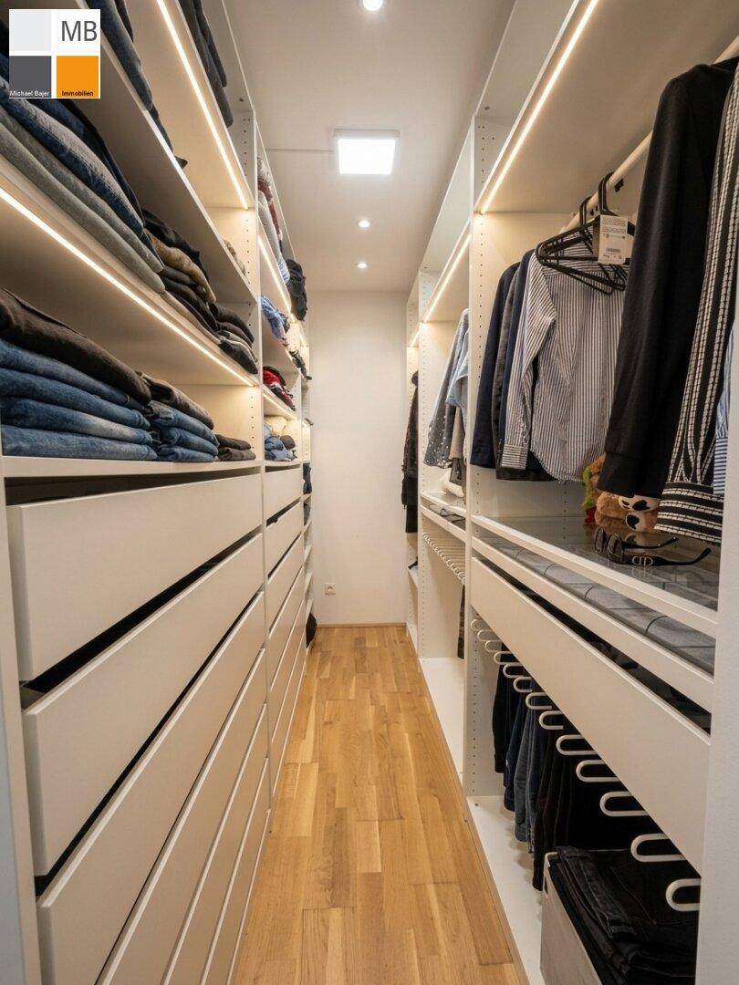 Begehbarer Kleiderschrank mit integrierten Regalen, Schubladen und Beleuchtung.