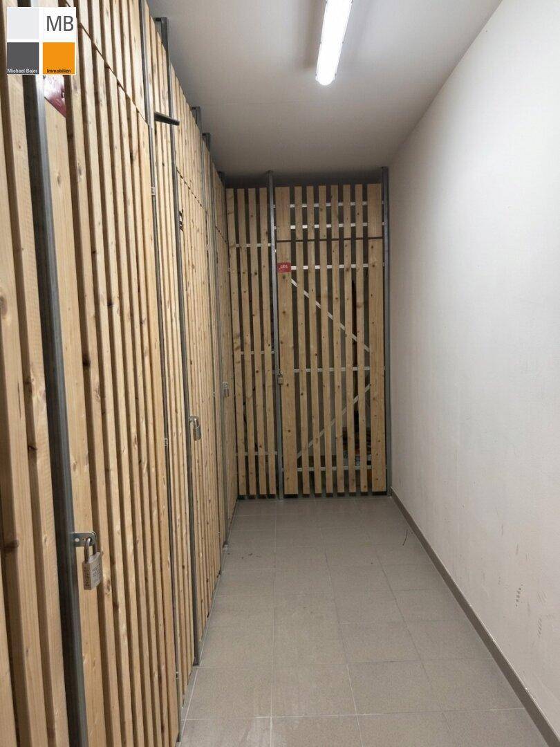 Kellerabteil mit Holzlattenwänden und gefliestem Boden für zusätzlichen Stauraum.