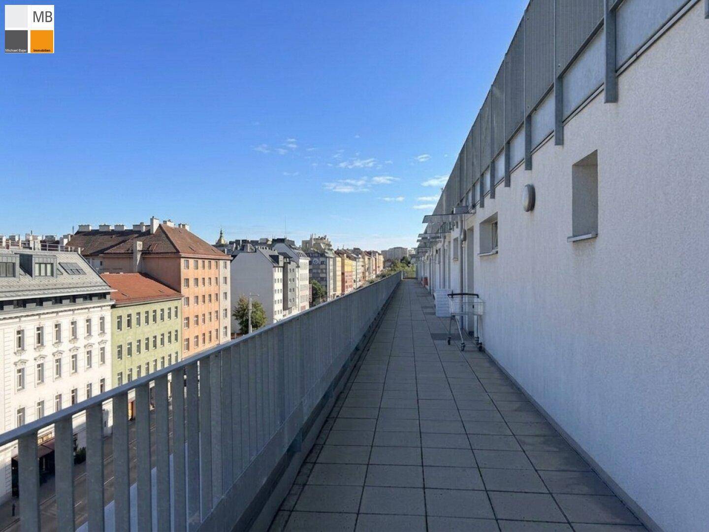 Langer Balkon mit Stadtblick, Metallgeländer und gefliestem Boden.