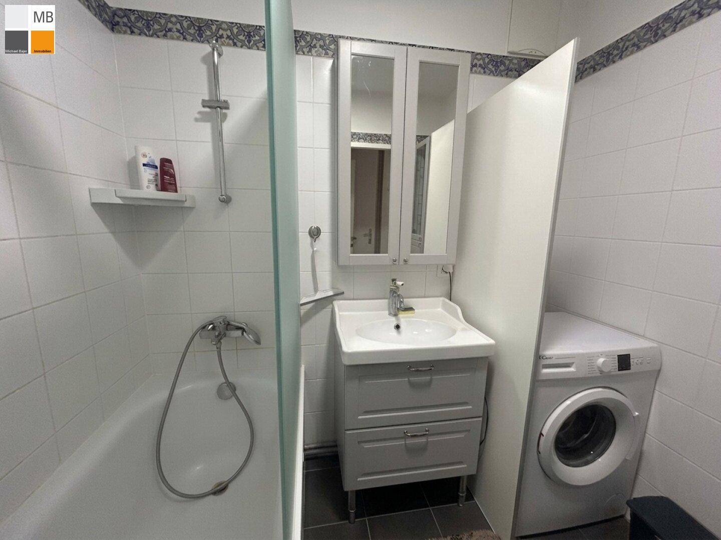 Funktionales Badezimmer mit Badewanne, Duschvorrichtung und Waschbecken mit Unterschrank.