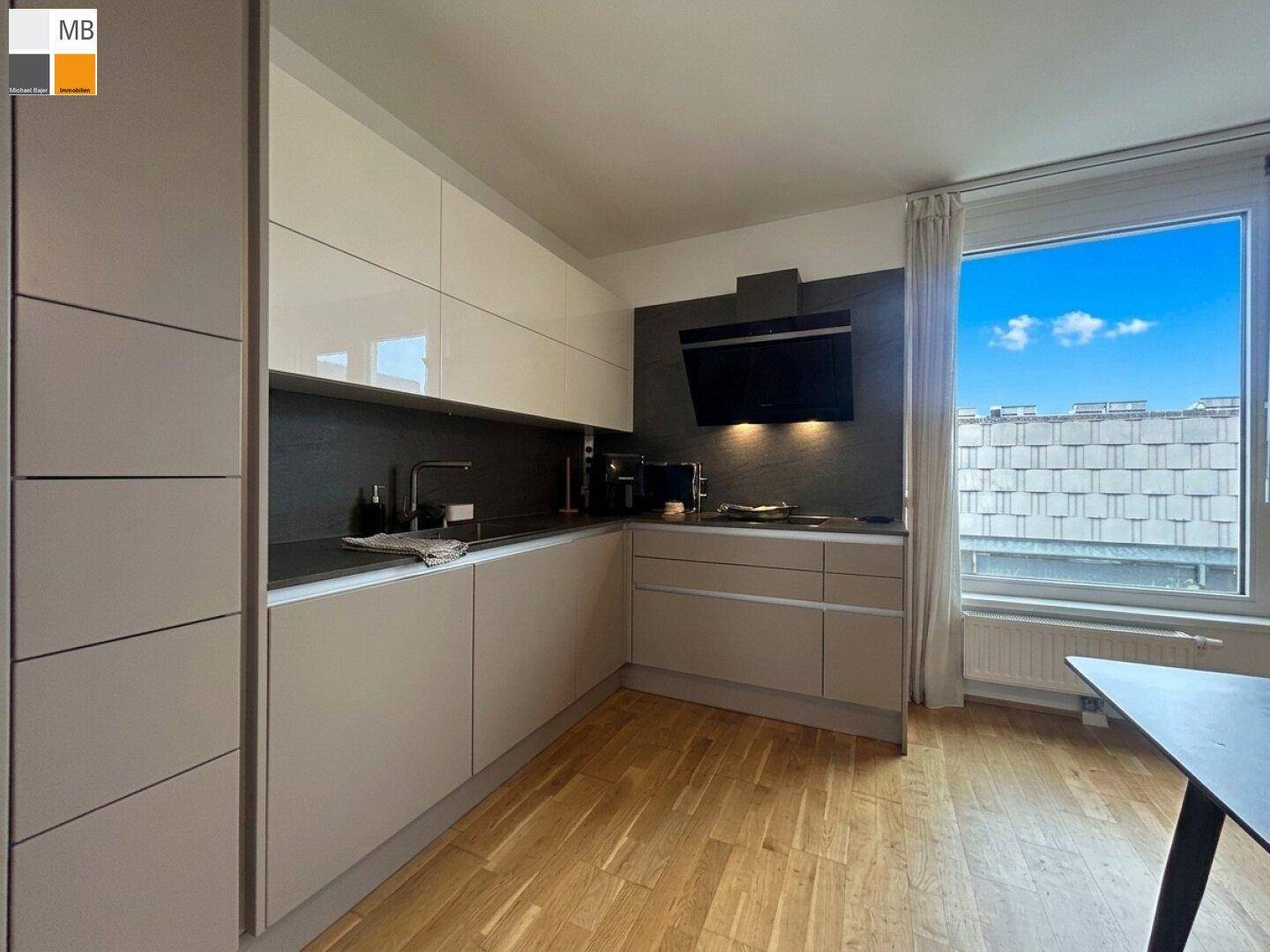 Moderne Einbauküche mit hellen Fronten, integrierten Geräten und Fenster mit Ausblick.