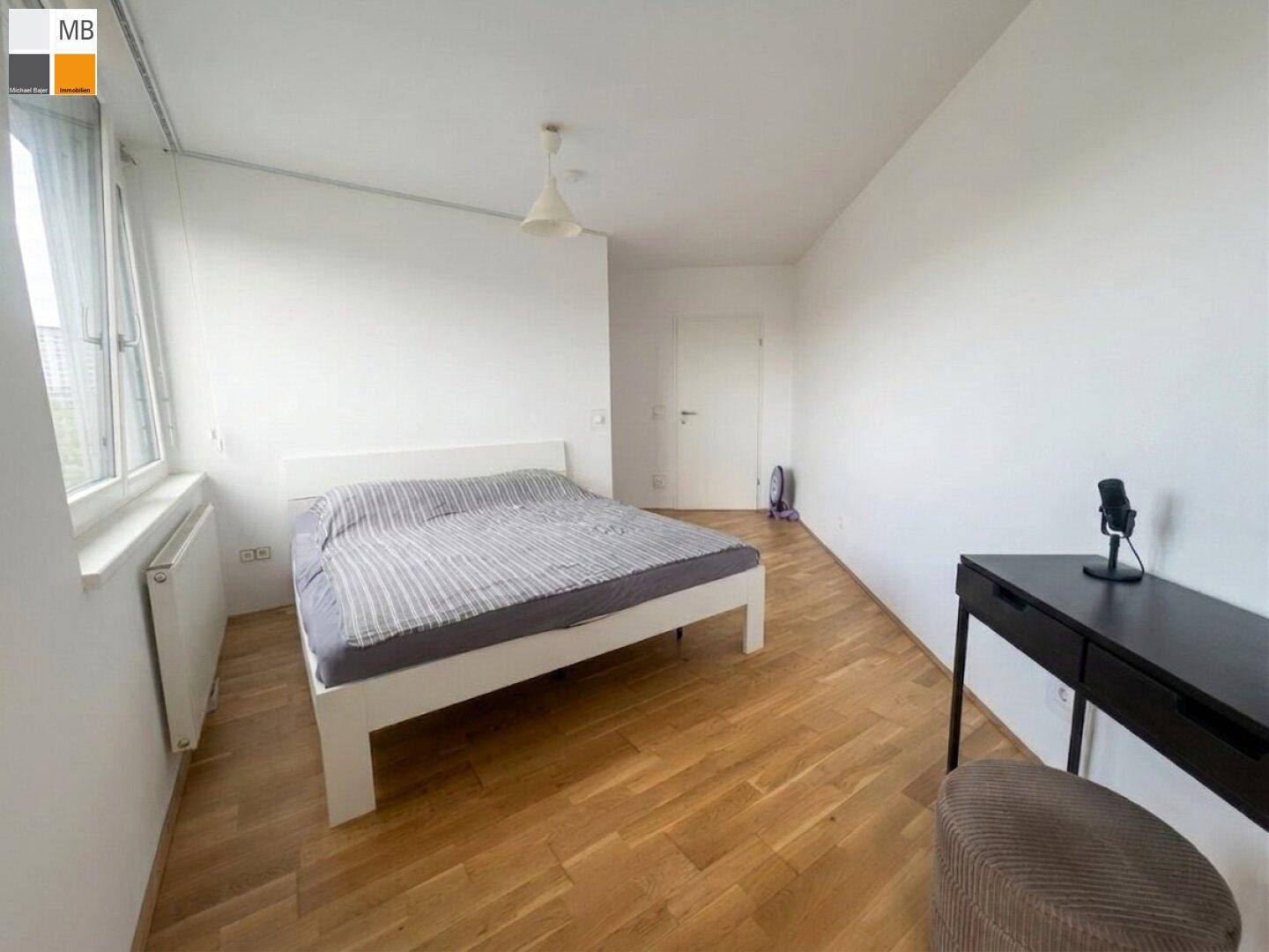 Geräumiges Schlafzimmer mit Parkettboden, weiß gestrichenen Wänden und viel Tageslicht.