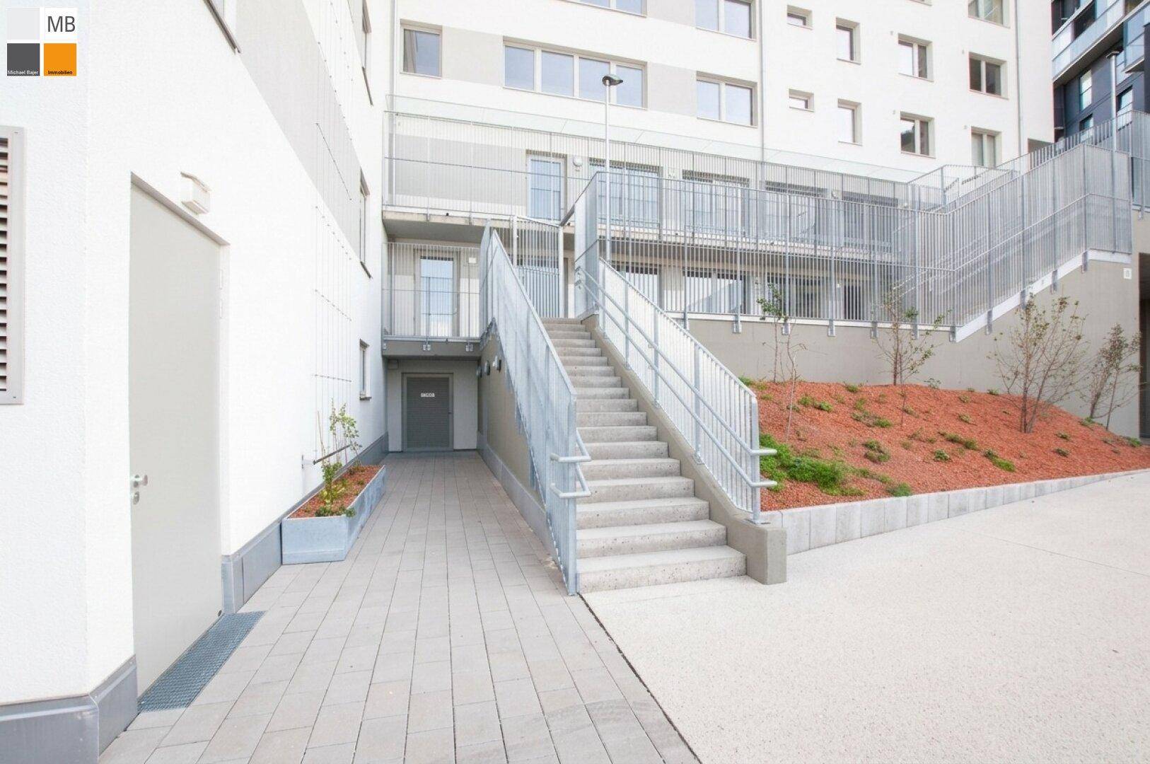 Außentreppe mit Metallgeländer und Zugang zu den Wohneinheiten in einem Neubau.