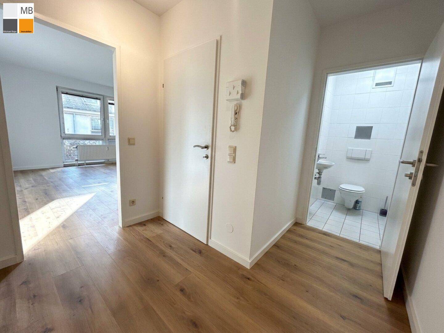 Heller Flur mit Laminatboden und Zugang zu weiteren Räumen, inklusive einem Gäste-WC.