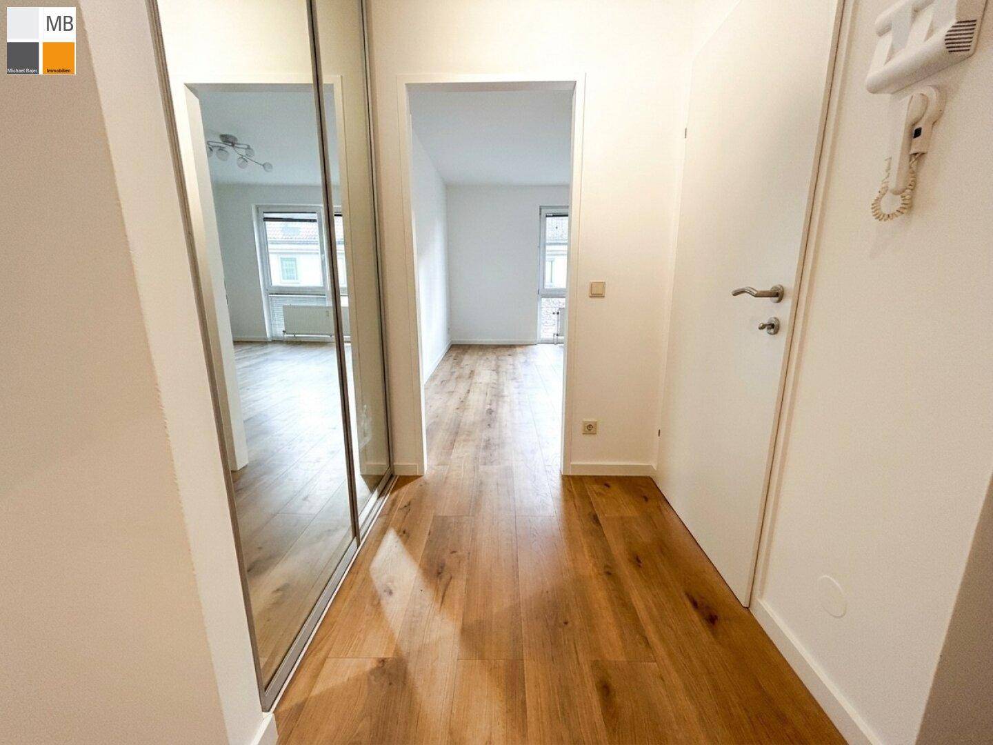 Geräumiger Flur mit Laminatboden und großem Spiegelschrank, der den Raum optisch erweitert.