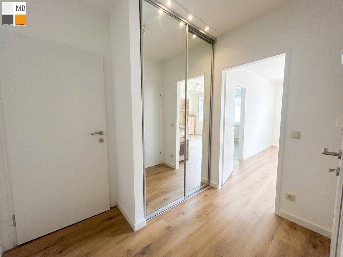 Heller Flur mit Laminatboden und integriertem Spiegelschrank, der viel Stauraum bietet.