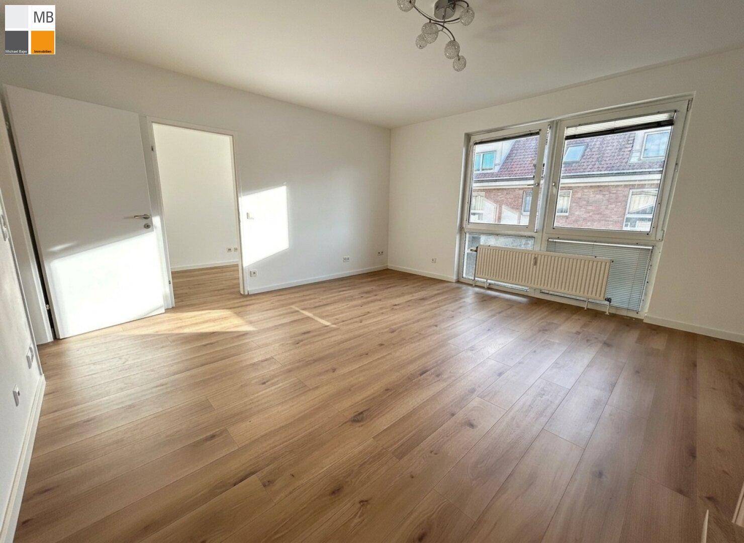 Helles Wohnzimmer mit Laminatboden und großen Fenstern, die einen Blick nach draußen ermöglichen.