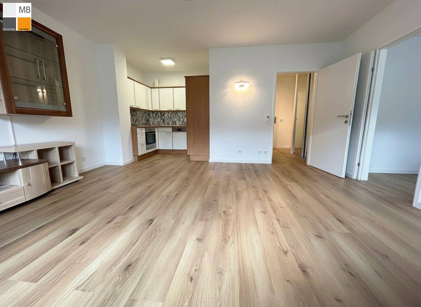 Offener Wohnbereich mit integrierter Küchenzeile und Laminatboden, bietet viel Platz und Helligkeit.