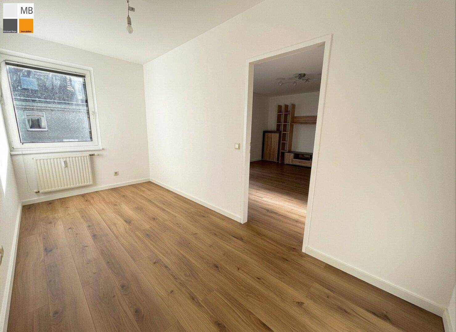 Schlafzimmer mit Laminatboden und Fenster, das viel Tageslicht hereinlässt, bereit zur individuellen Gestaltung.