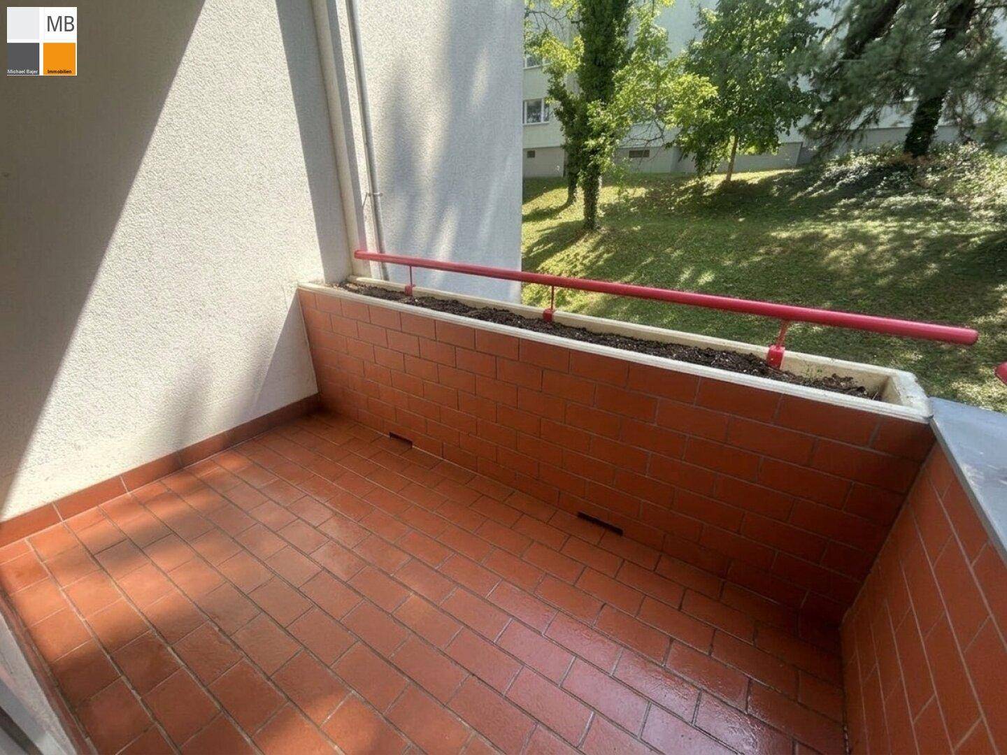 Geräumiger Balkon mit Terrakottafliesen und rotem Geländer, bereit für individuelle Gestaltung.