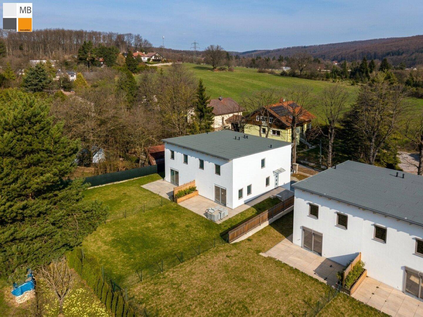Luftaufnahme von zwei modernen Häusern in einer grünen, ländlichen Umgebung mit weitem Blick.
