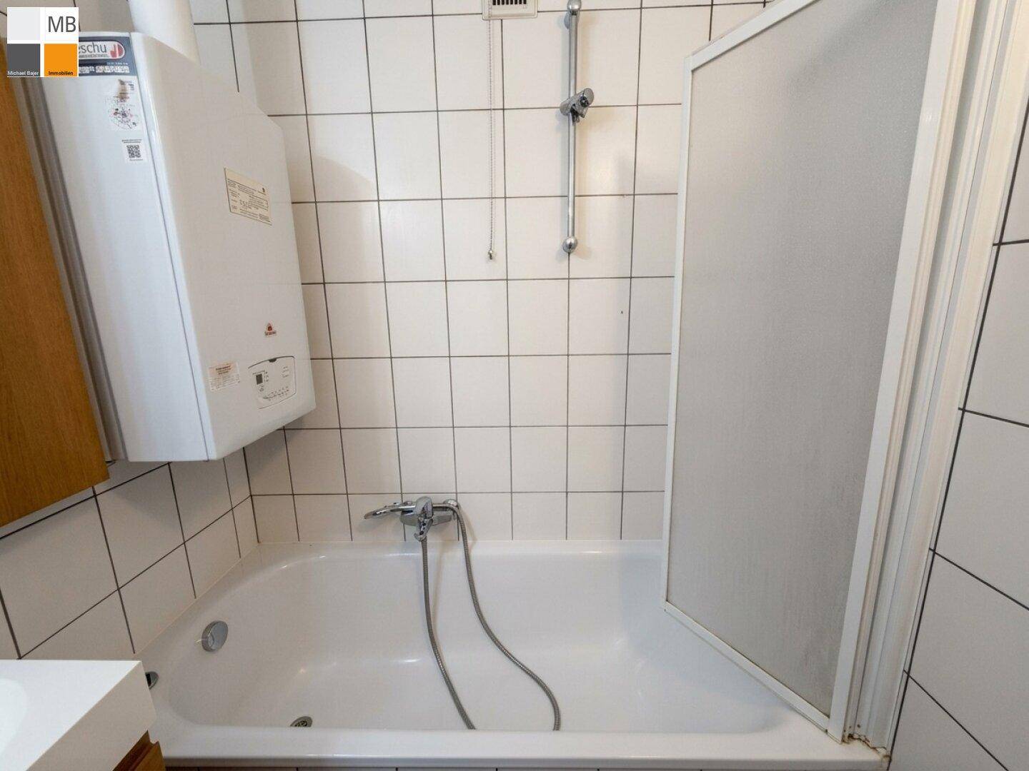 Badezimmer mit Badewanne, Duschabtrennung und weißen Fliesen.