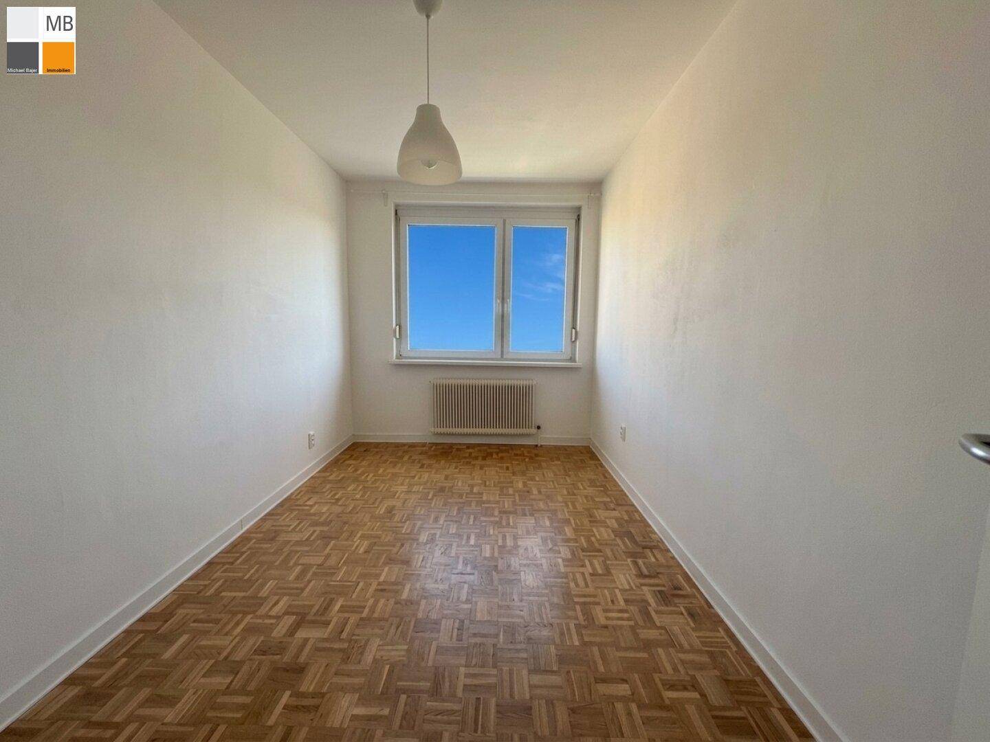 Schlafzimmer mit hellem Parkettboden und großem Fenster für viel Tageslicht.