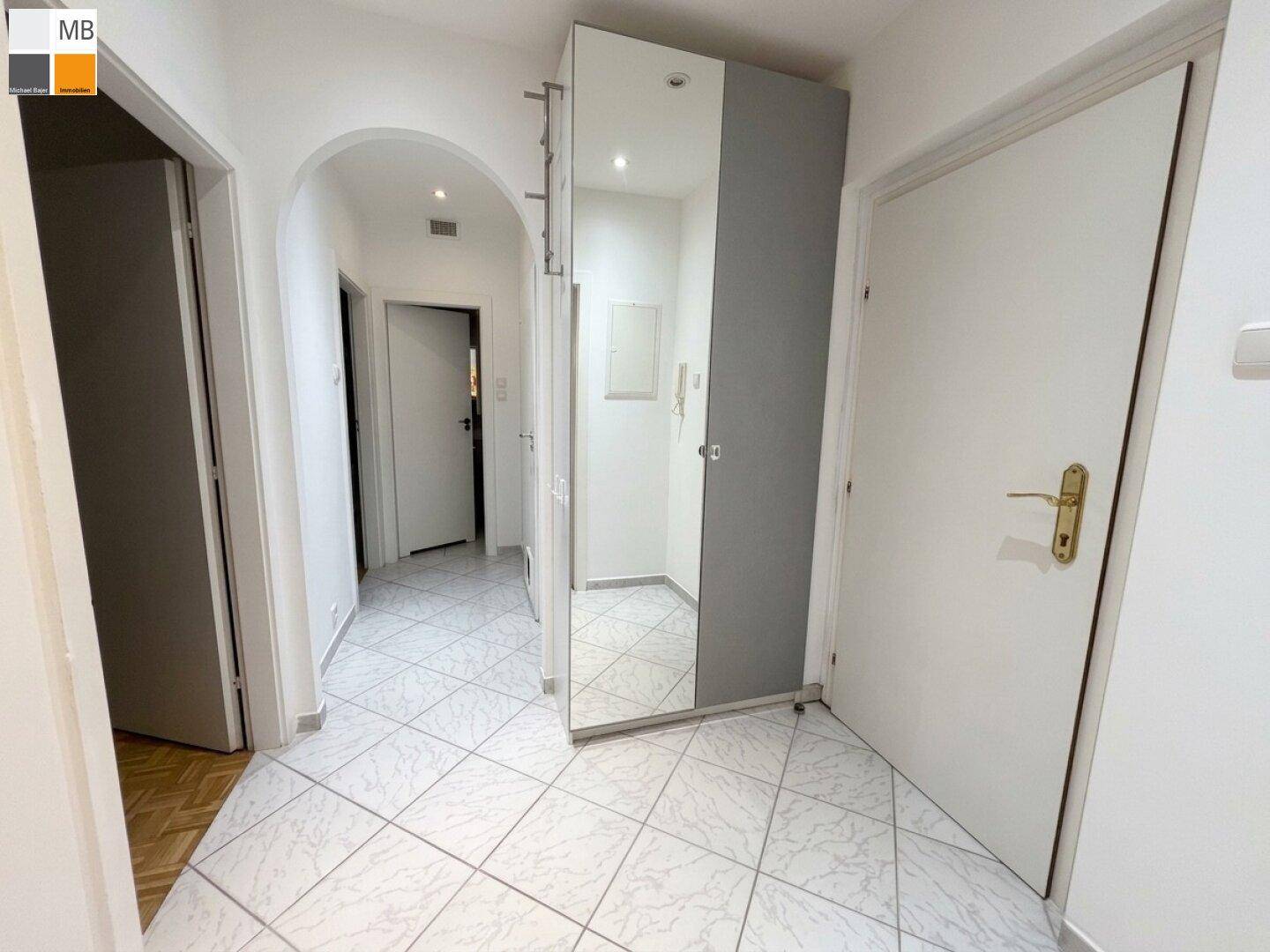 Flur mit hellen Fliesen und einem großen Spiegelschrank.