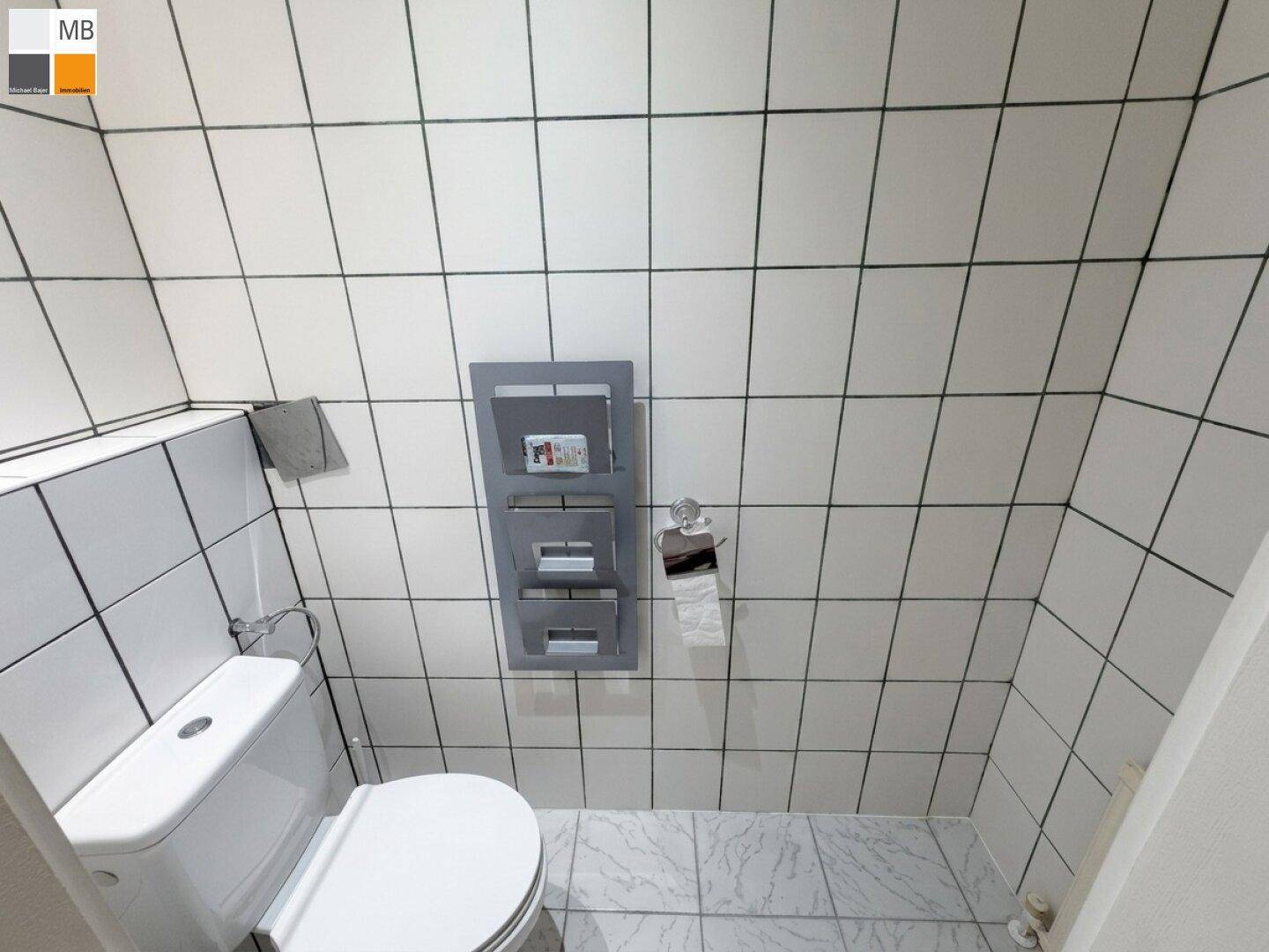 Kleines WC mit weißen Fliesen und Wand-WC.