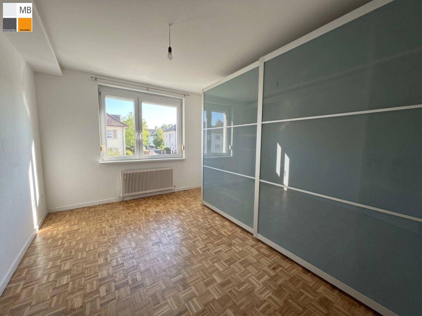 Schlafzimmer mit Parkettboden und großem Schiebeschrank mit Spiegelfronten.