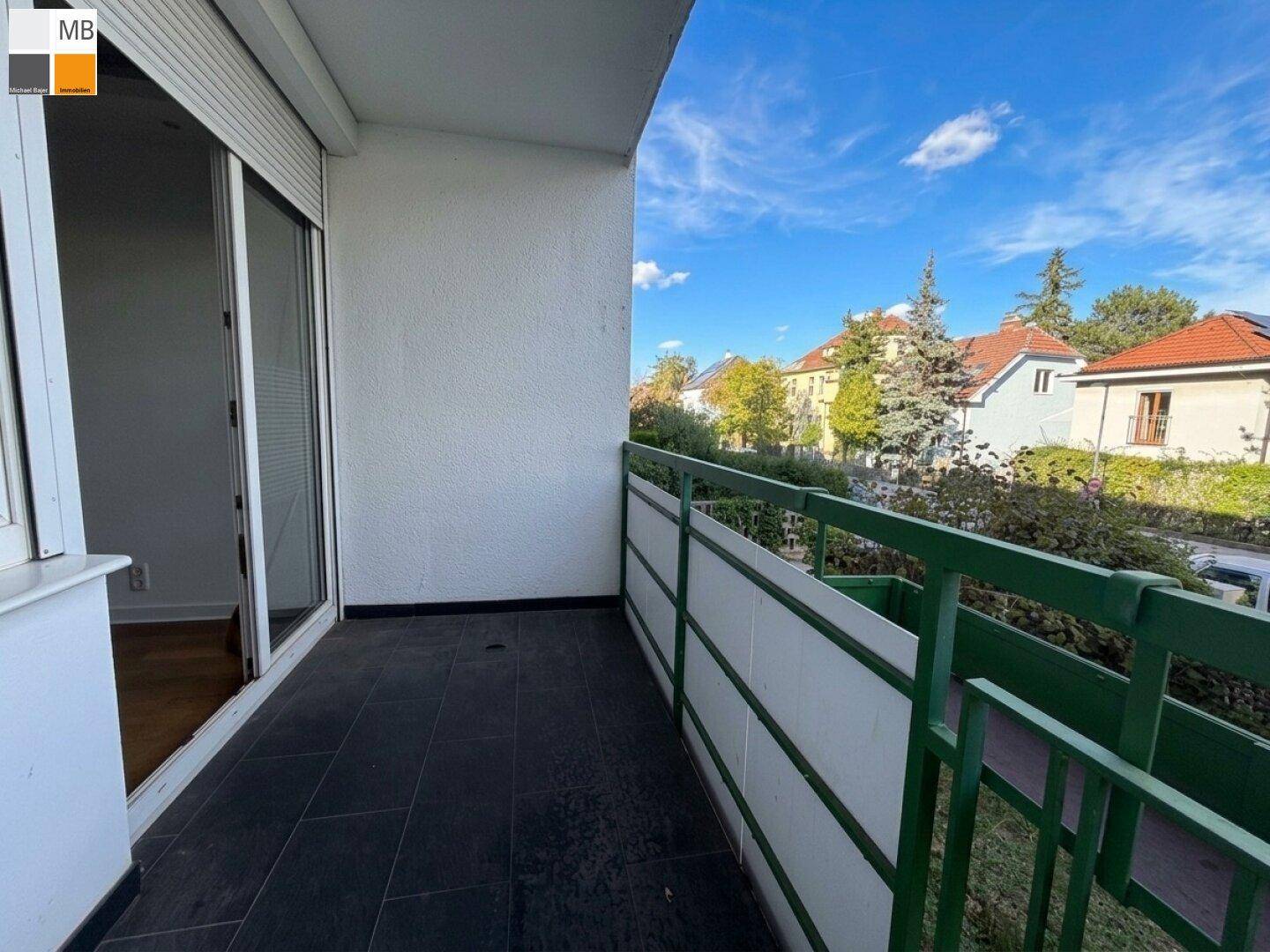 Geräumiger Balkon mit Fliesenboden und Blick auf die grüne Umgebung.