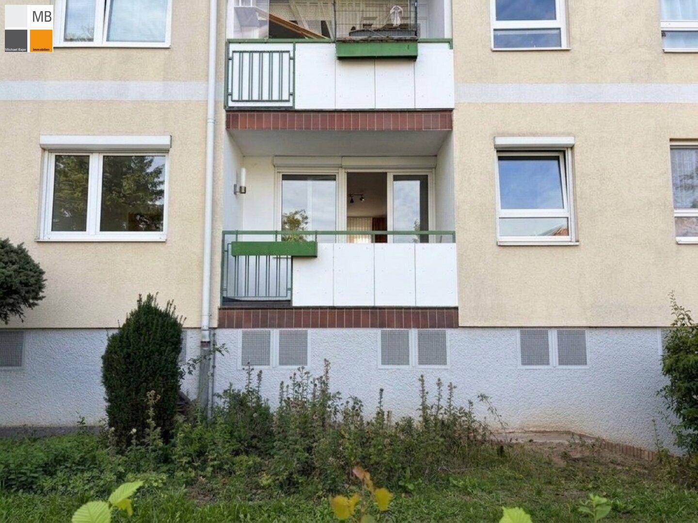 Fassade eines Mehrfamilienhauses mit Balkonen und Fenstern.