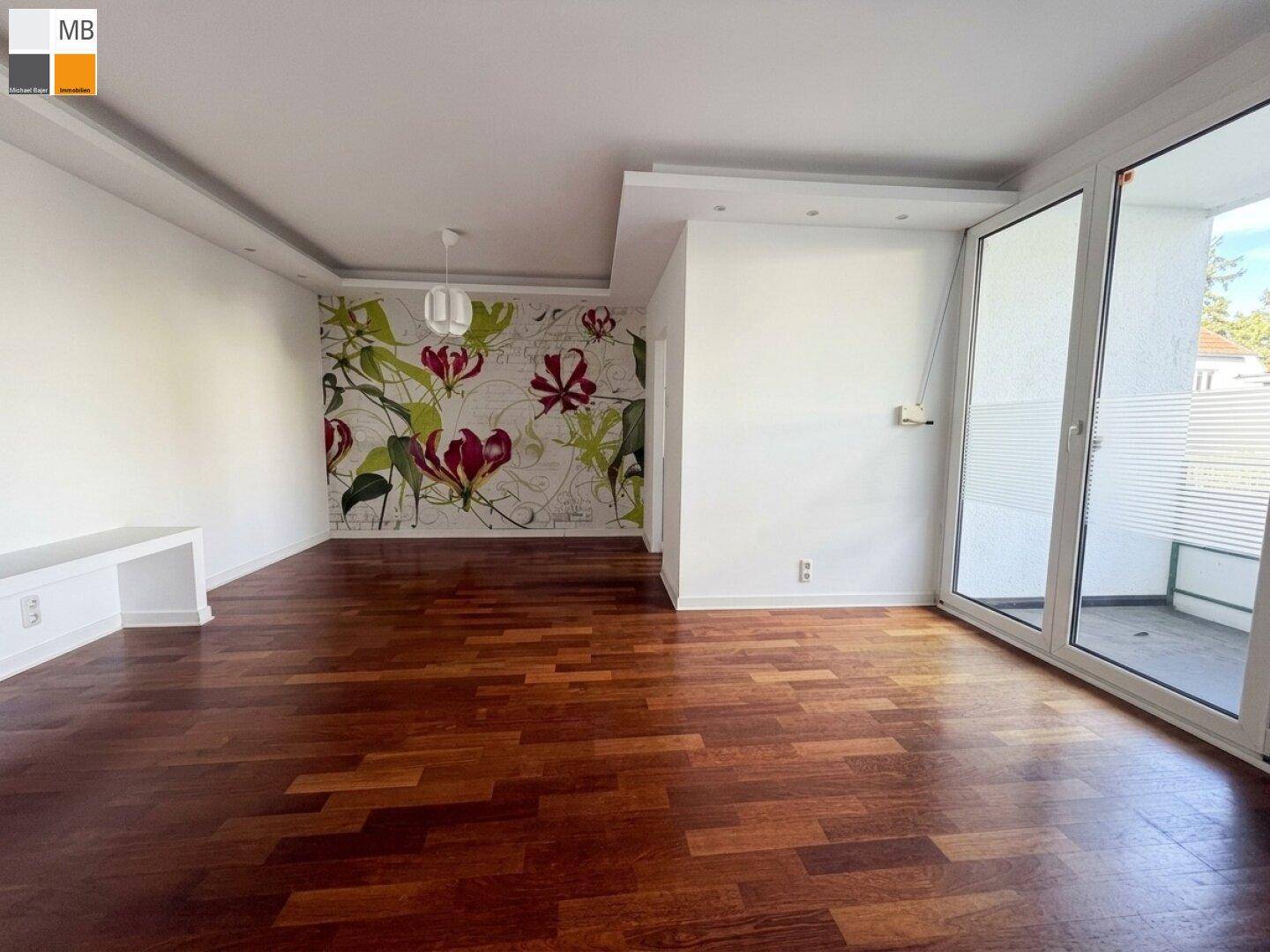 Helles Wohnzimmer mit dunklem Parkettboden und dekorativer Blumen-Tapete.