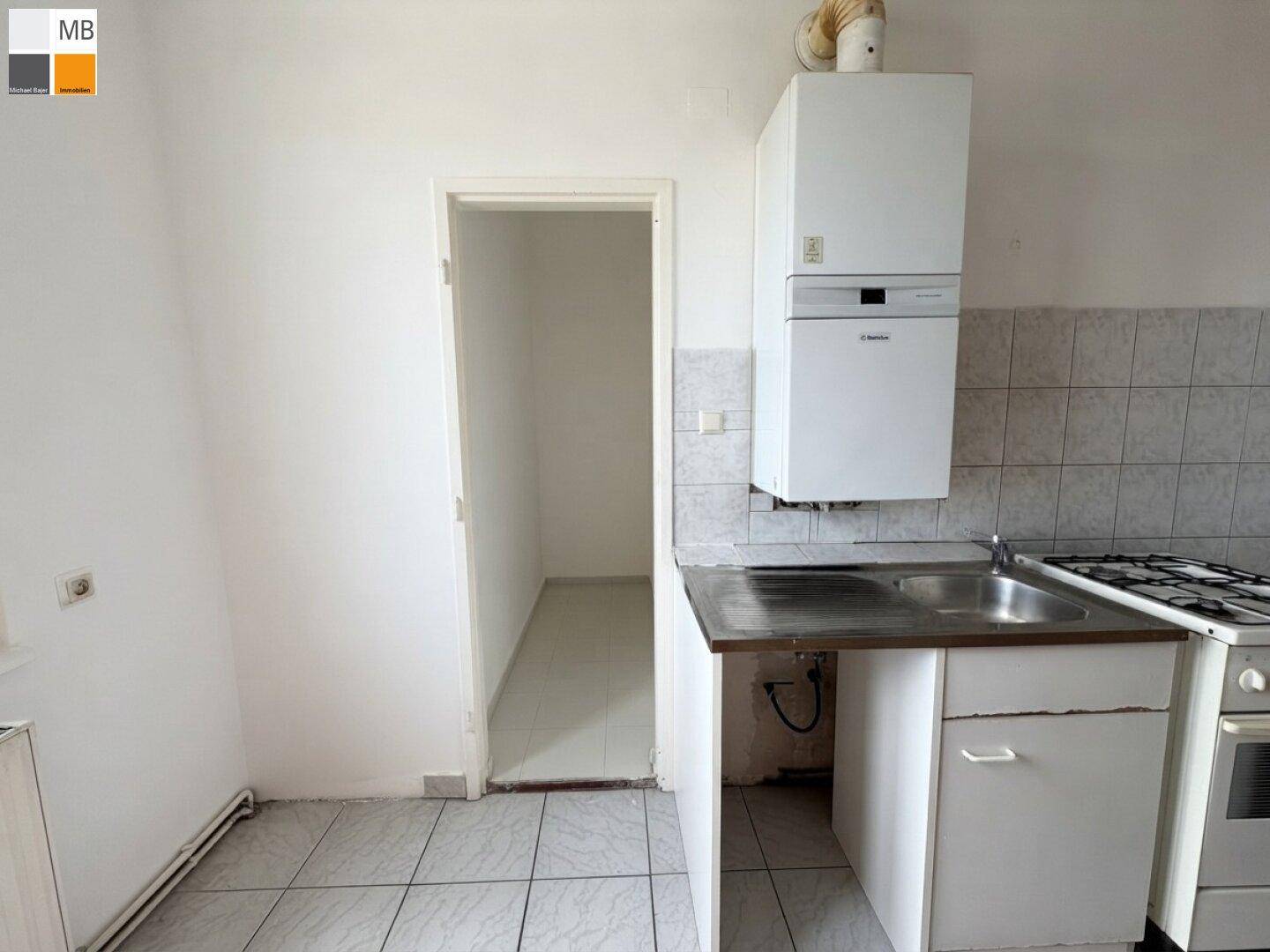 Küche mit Gastherme, Spüle und Zugang zu einem praktischen Abstellraum.