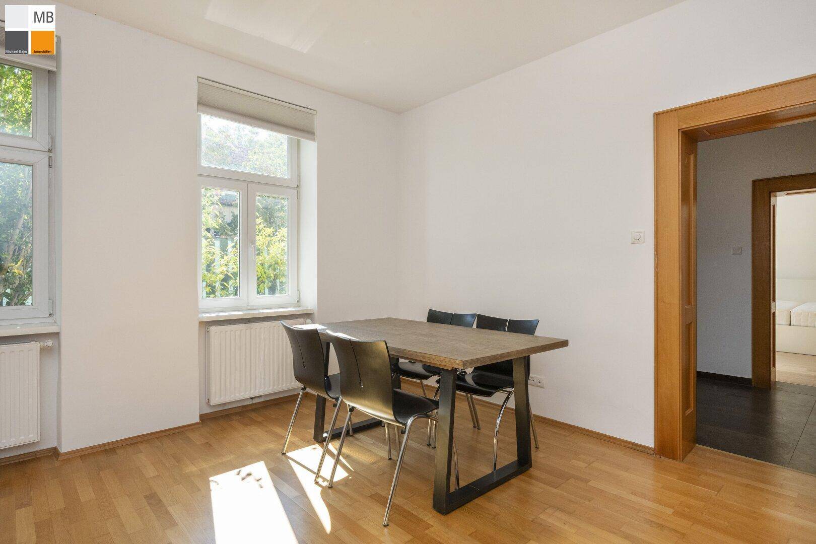 Heller Essbereich mit Holzboden, großem Fenster und modernem Esstisch.