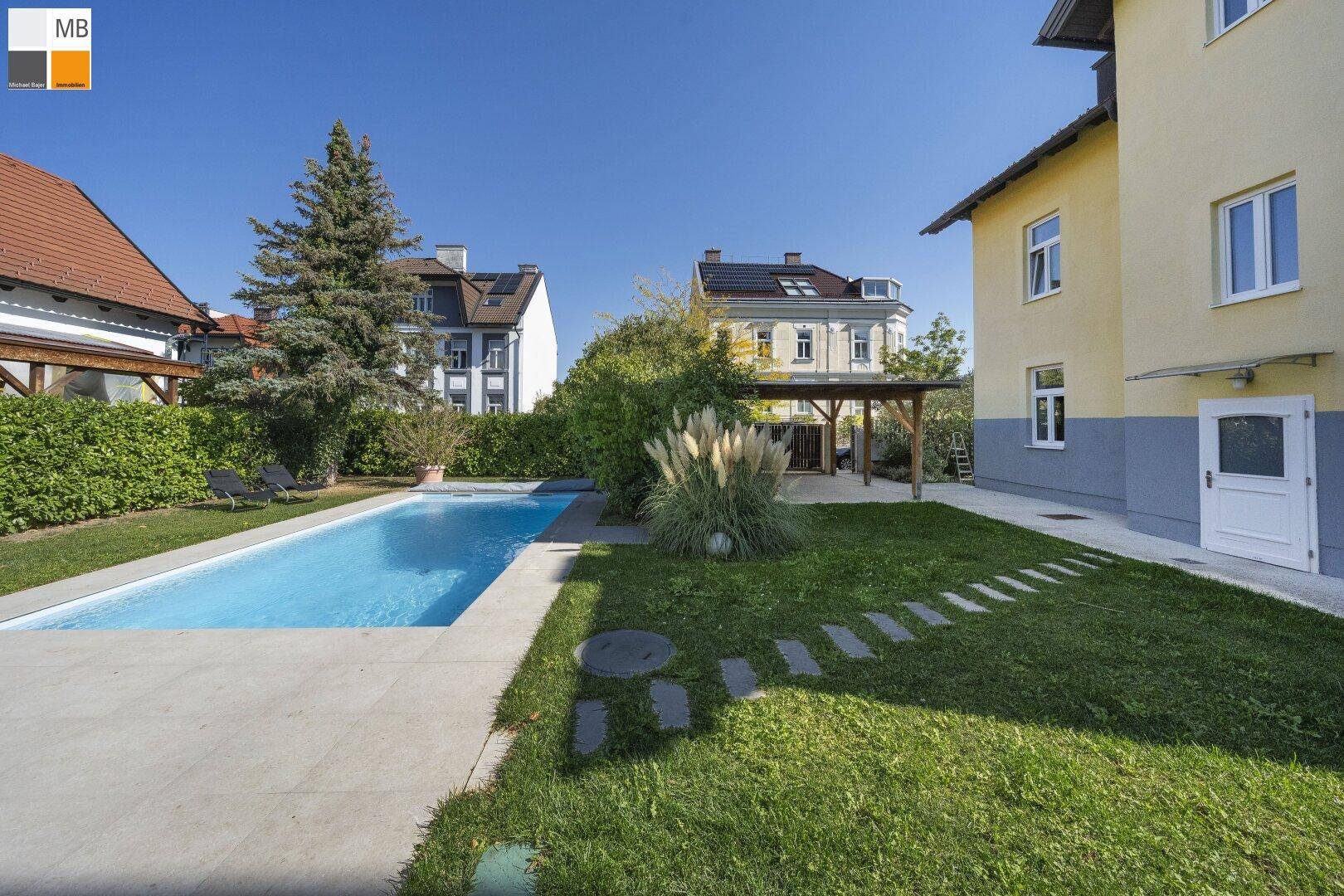 Großer Gartenbereich mit Swimmingpool, Liegewiese und sonnigen Terrassenflächen.