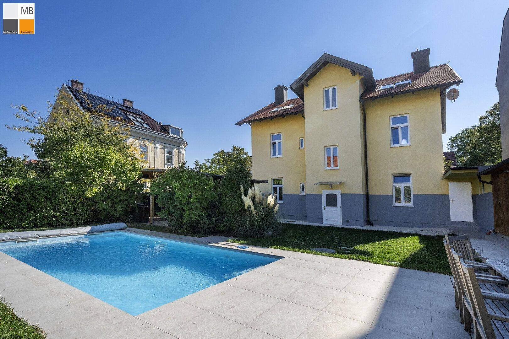 Weitläufiger Garten mit großem Pool und angrenzender Terrasse, ideal für Entspannung.