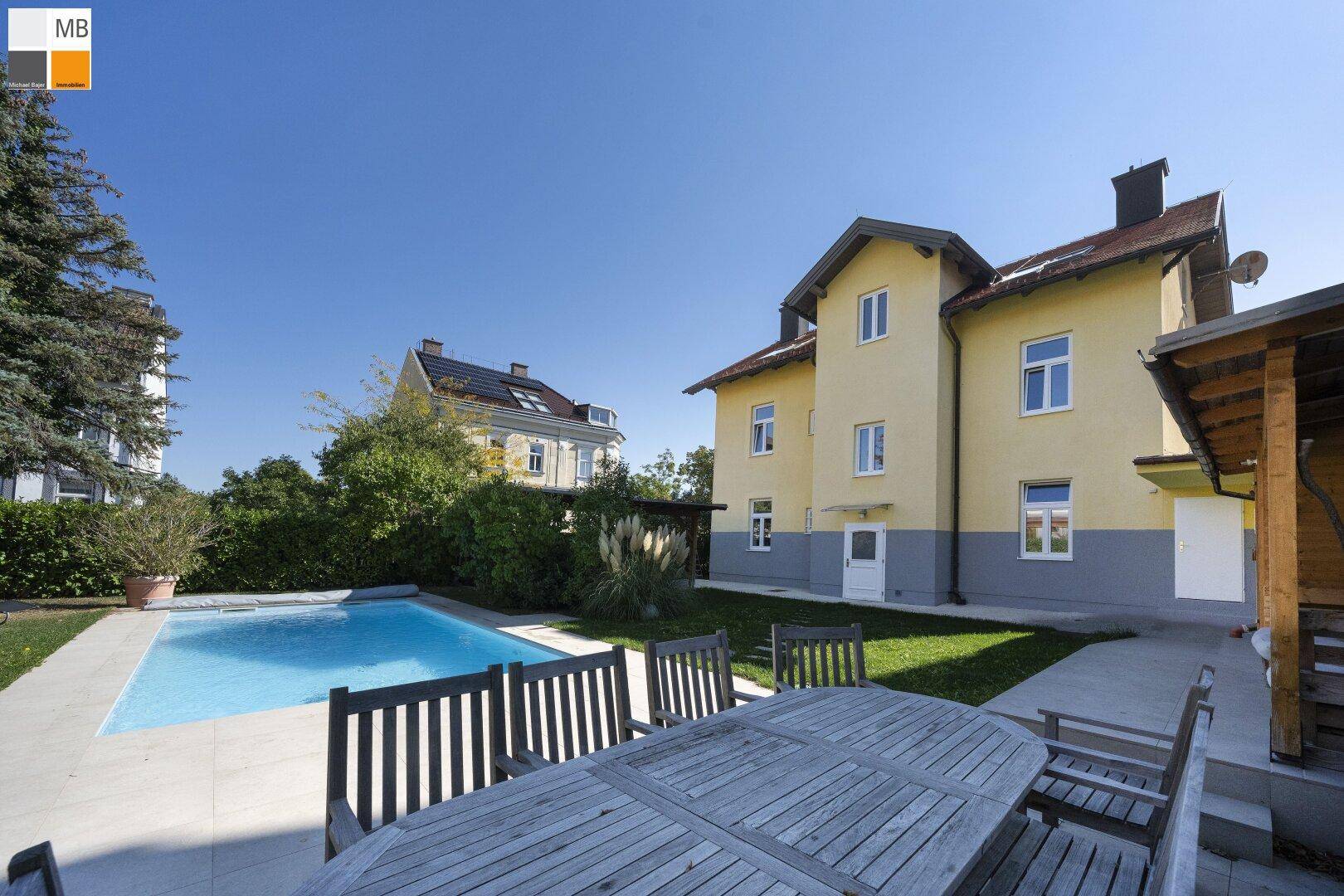 Sonniger Garten mit Pool und großem Esstisch im Freien für gesellige Stunden.