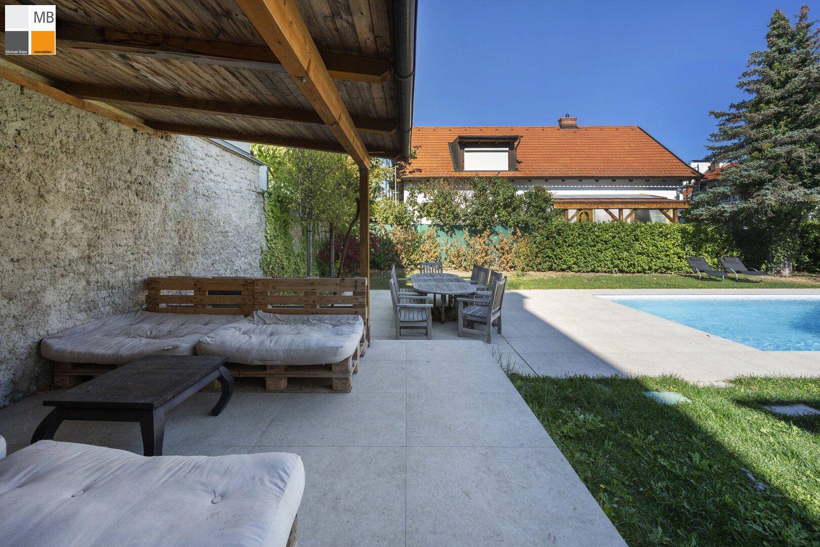 Überdachte Terrasse mit Lounge-Möbeln und Essbereich direkt am Swimmingpool.