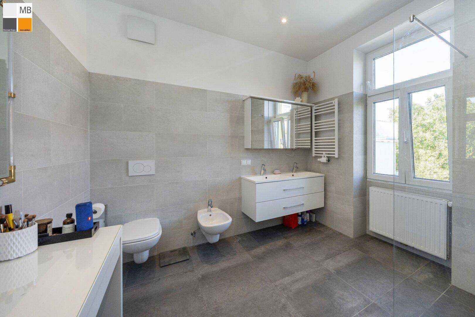 Modernes Badezimmer mit Doppelwaschbecken, Bidet, WC und großer Dusche.