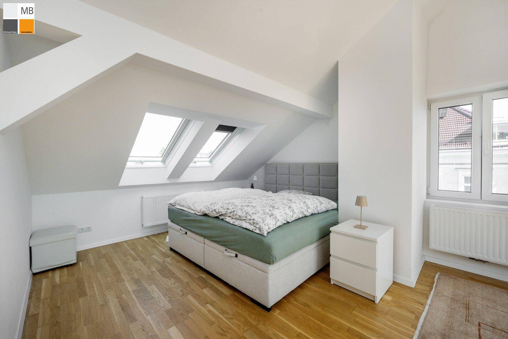 Helles Schlafzimmer im Dachgeschoss mit Holzboden, Dachfenstern und viel natürlichem Licht.