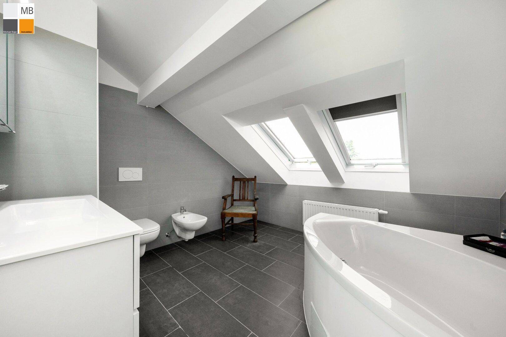 Helles Badezimmer im Dachgeschoss mit Bidet, Eckbadewanne und Dachfenstern für Tageslicht.