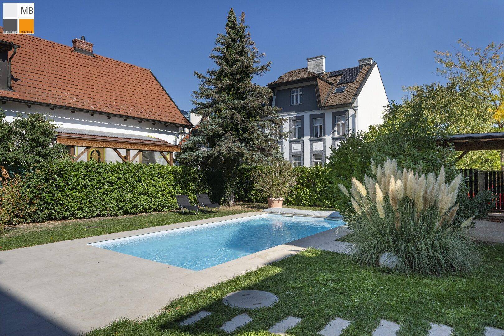 Gepflegter Garten mit Swimmingpool, Liegestühlen und üppiger Bepflanzung.