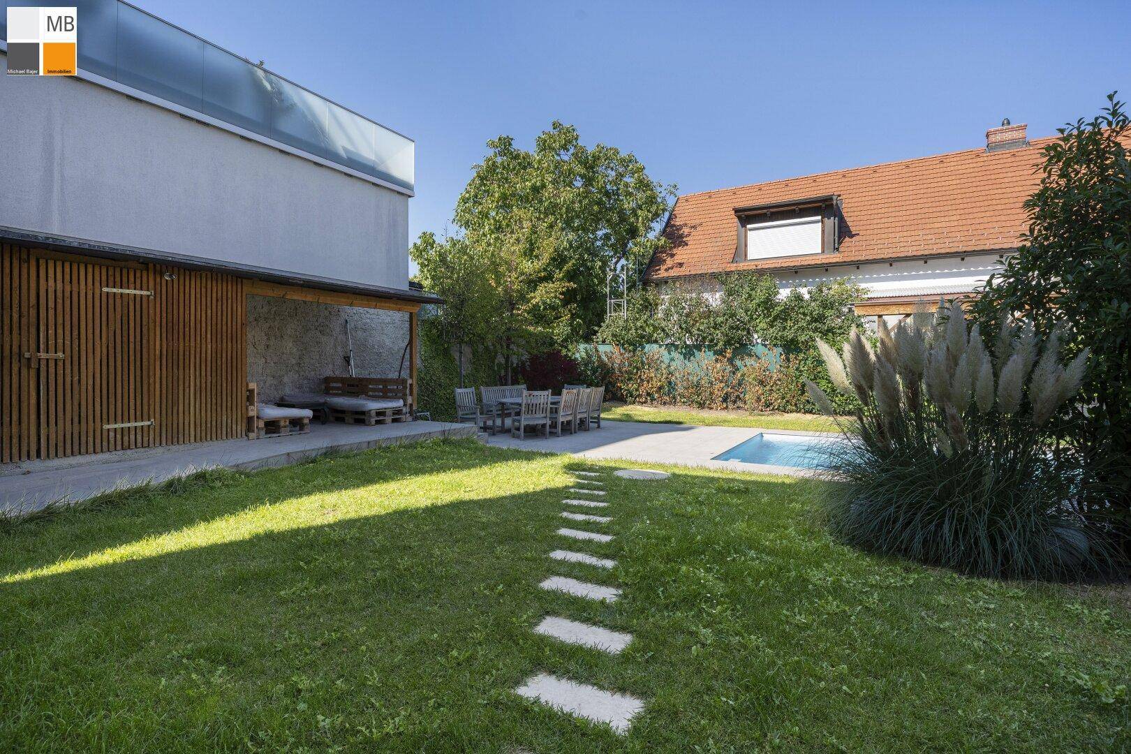 Großer Garten mit Pool, Essbereich im Freien und gepflegter Rasenfläche.