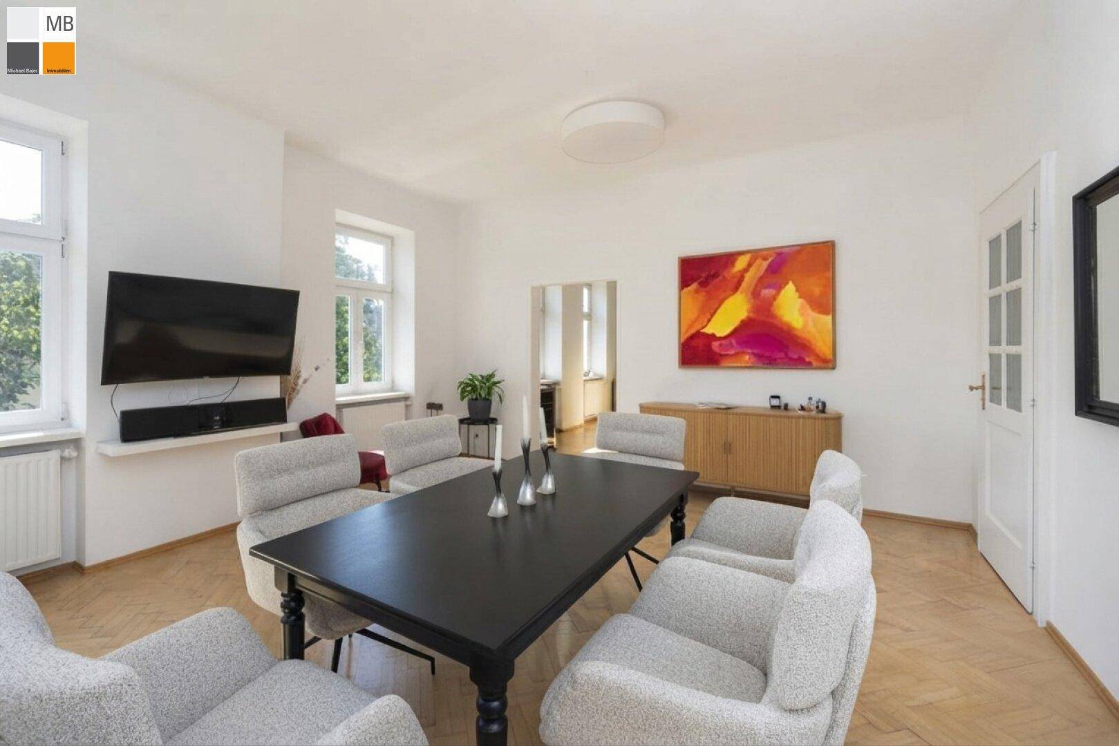 Eleganter Wohn-Essbereich mit dunklem Esstisch und moderner Kunst an der Wand.