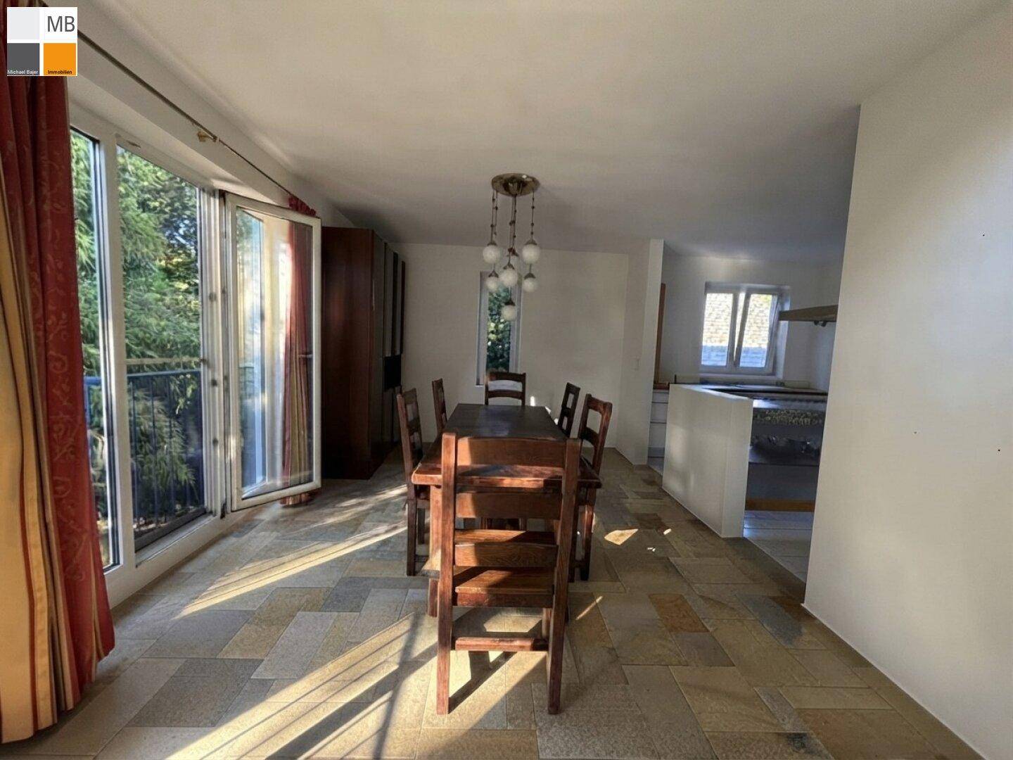 Heller Essbereich mit Holztisch und Zugang zu einem Balkon, ausgestattet mit großen Fenstern.