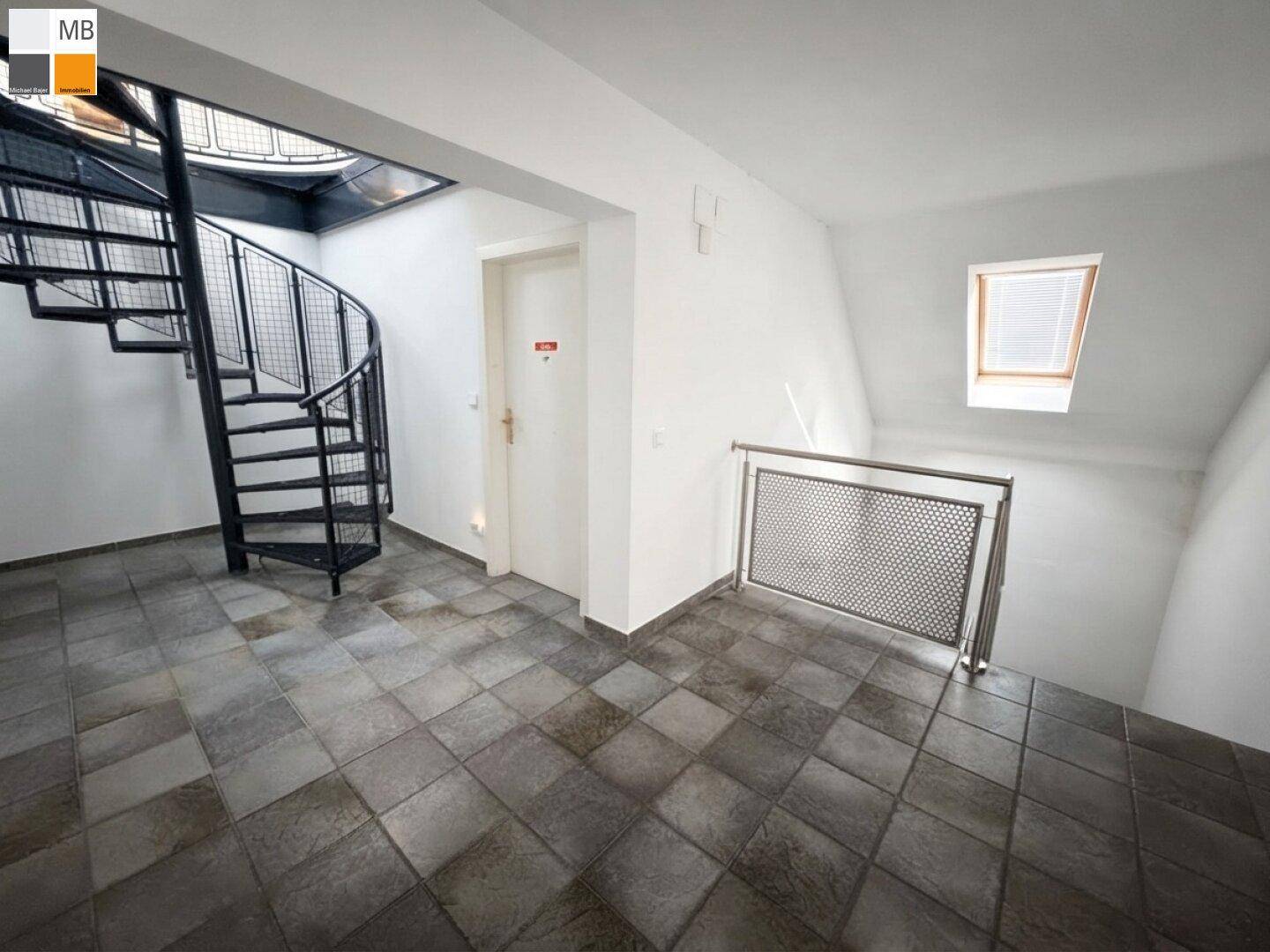 Geräumiger Flur mit Wendeltreppe, gefliestem Boden und einem Dachfenster für natürliches Licht.