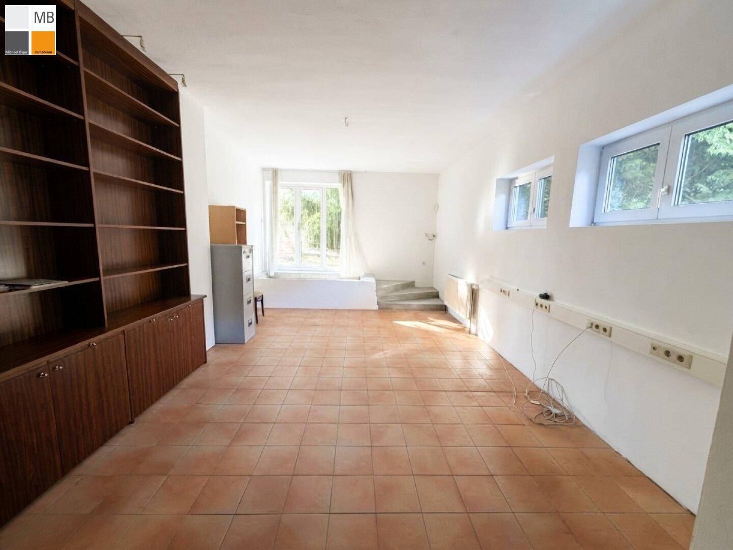 Vielseitiger Raum mit Terrakotta-Fliesenboden und großem Bücherregal, bietet viel Stauraum.