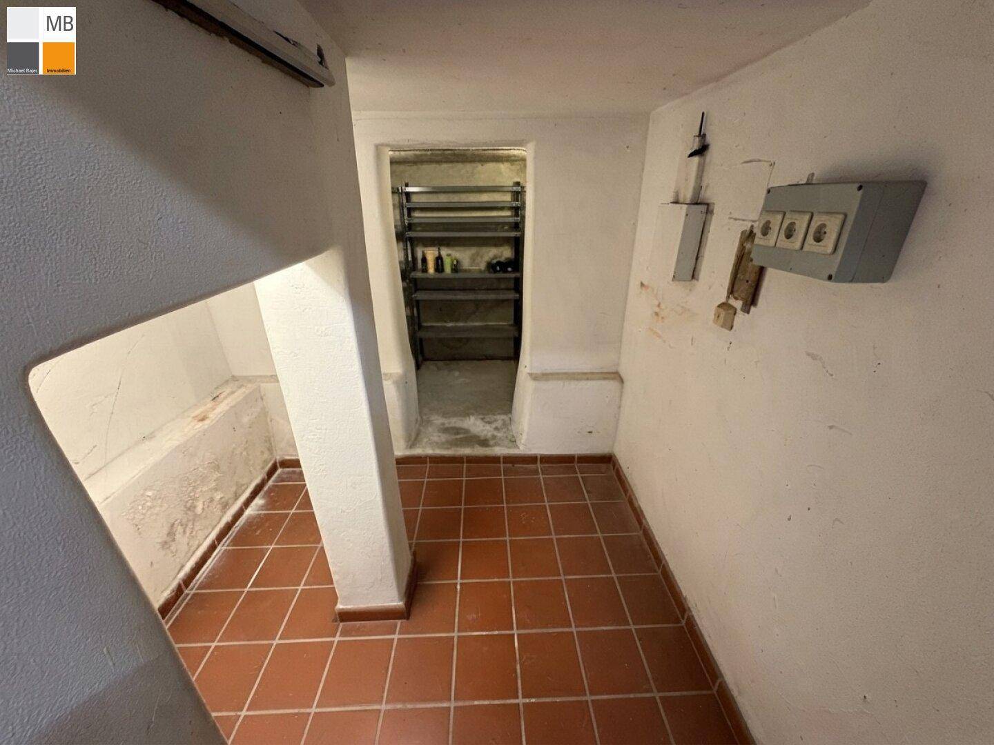 Kellerraum mit Fliesenboden und Regalen, bietet zusätzlichen Stauraum für diverse Gegenstände.