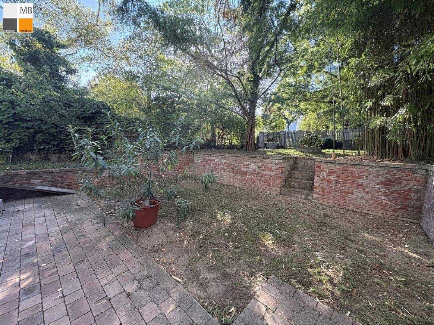 Gepflegter Gartenbereich mit Ziegelmauern, gepflasterten Wegen und üppiger Bepflanzung.