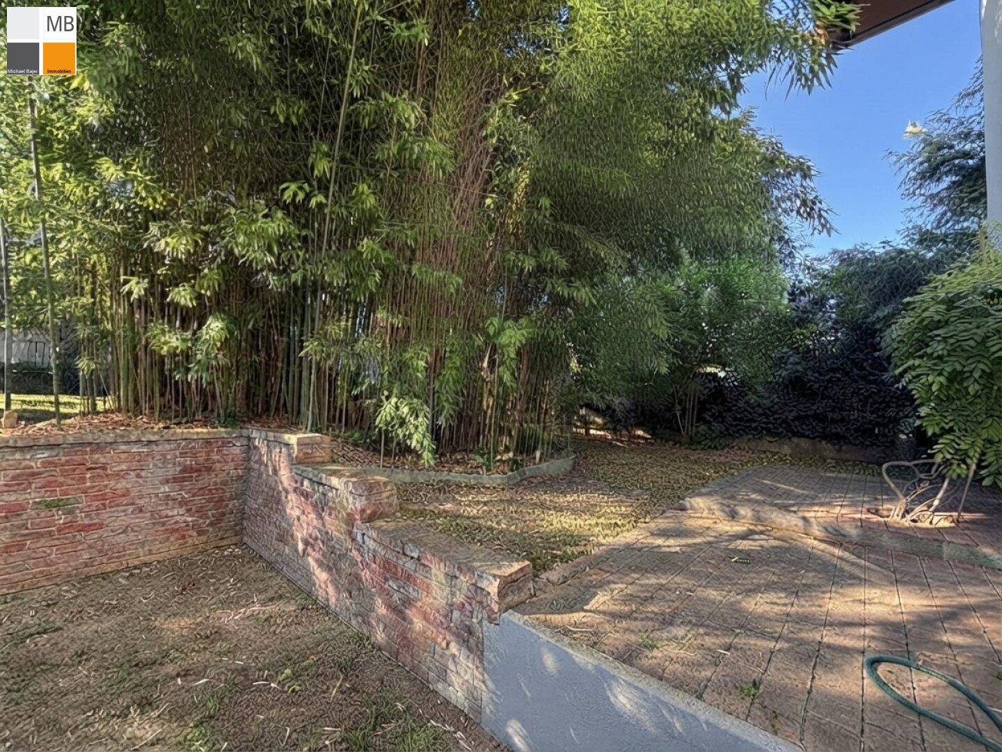 Grüner Garten mit Bambuspflanzen und Ziegelmauern, bietet eine ruhige und natürliche Umgebung.