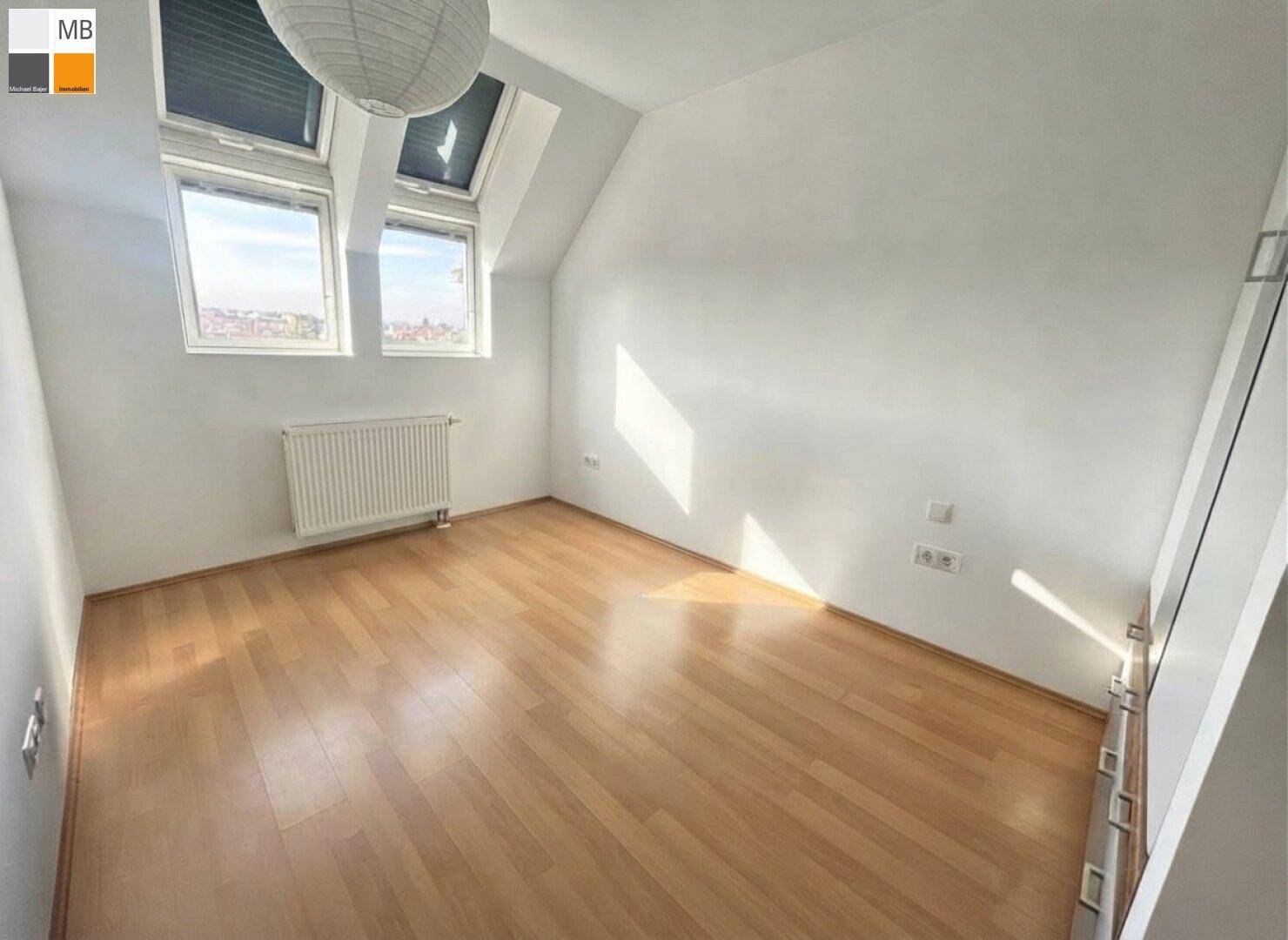 Helles Zimmer im Dachgeschoss mit schrägen Wänden und Dachfenstern, bietet viel Tageslicht.