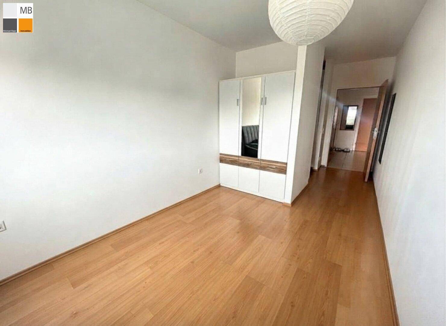 Schlafzimmer mit Holzboden und einem Kleiderschrank, hell und funktional eingerichtet.