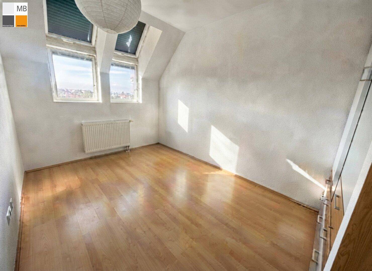 Helles Schlafzimmer im Dachgeschoss mit Holzboden und Dachfenstern für viel Tageslicht.