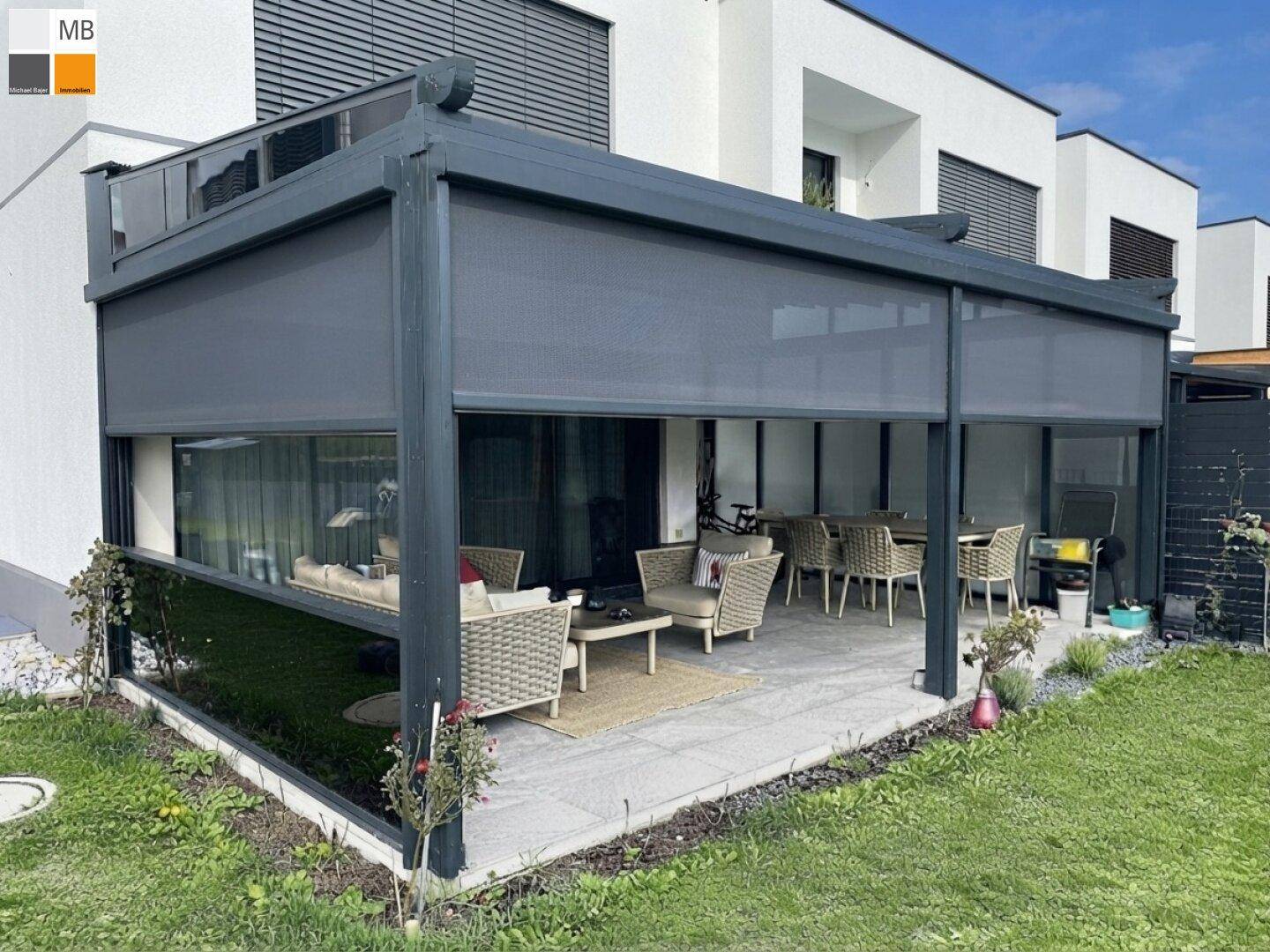 Geräumige, überdachte Terrasse mit modernen Gartenmöbeln und ausfahrbaren Seitenwänden.