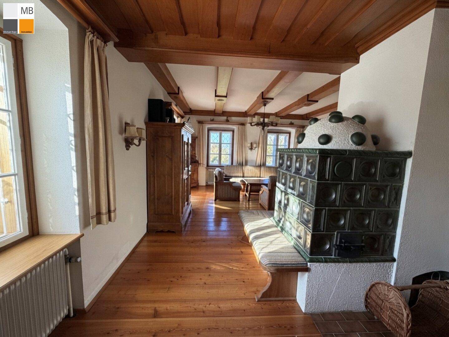 Traditioneller Kachelofen als Herzstück des Wohnbereichs mit Holzdielenboden und rustikalen Möbeln.